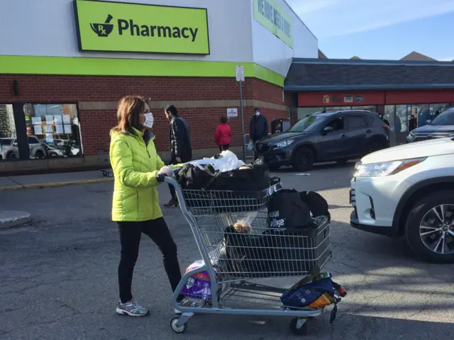 Woman wearing a face mask and surgical gloves to protect her from the novel coronavirus while grocery shopping in Toronto, Ontario, Canada