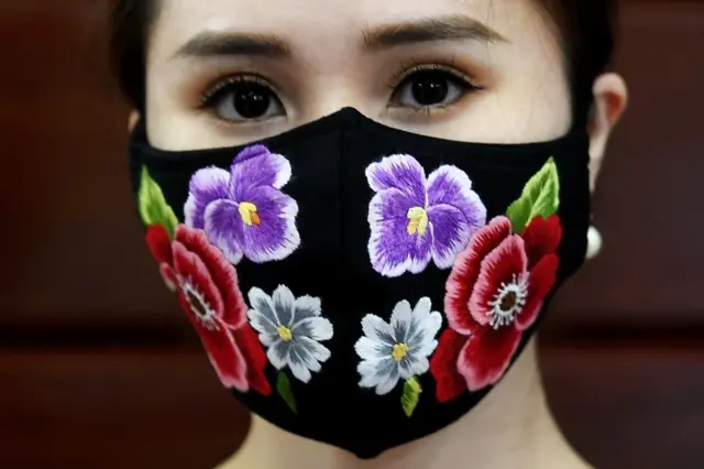 A model poses wearing designer Do Quyen Hoa"s colourful hand-embroidered face masks, used as a preventive measure against the spread of the COVID-19 novel coronavirus, at her workshop in Hanoi on April 13, 2020.