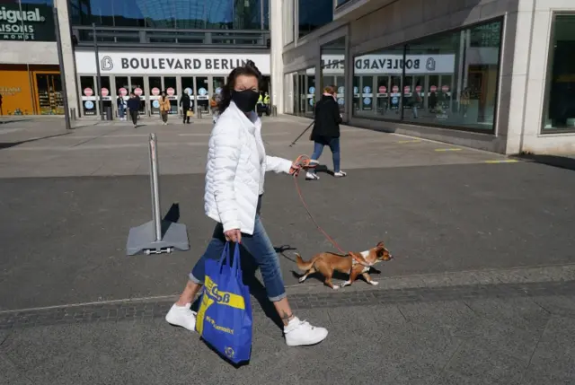 A woman in a face mask walks her dog in Berlin