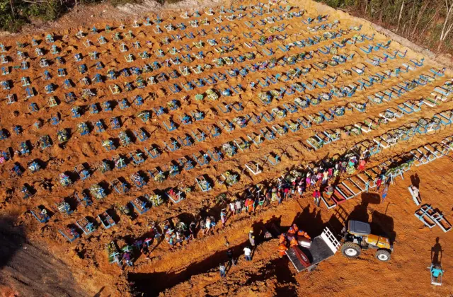 Aerial view of cemetery workers unloading a coffin from a truck at an area where new graves have been dug at the Parque Taruma cemetery, Amazonas state