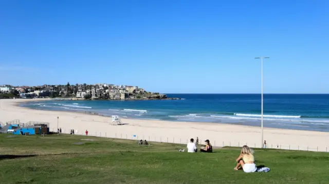 People sit on the grass next to a shut-down Bondi Beach on 21 April 2020