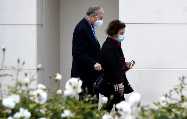 A couple wearing masks walk along Rodeo Drive in Beverly Hills