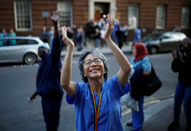 An NHS worker applauds at St Mary's Hospital in London