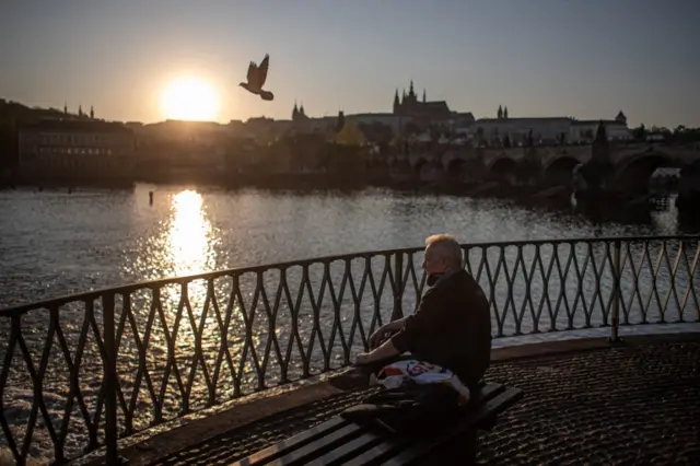 A man sits on bank of Vltava River at sunset in Prague, the Czech Republic. Photo: 23 April 2020