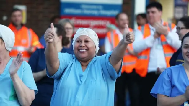 A healthcare worker smiling with her thumbs up