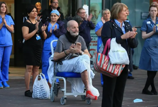 A patient in a wheelchair claps outside the Royal Derby Hospital