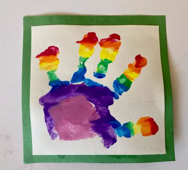 Photograph shows a rainbow handprint on homemade craft design