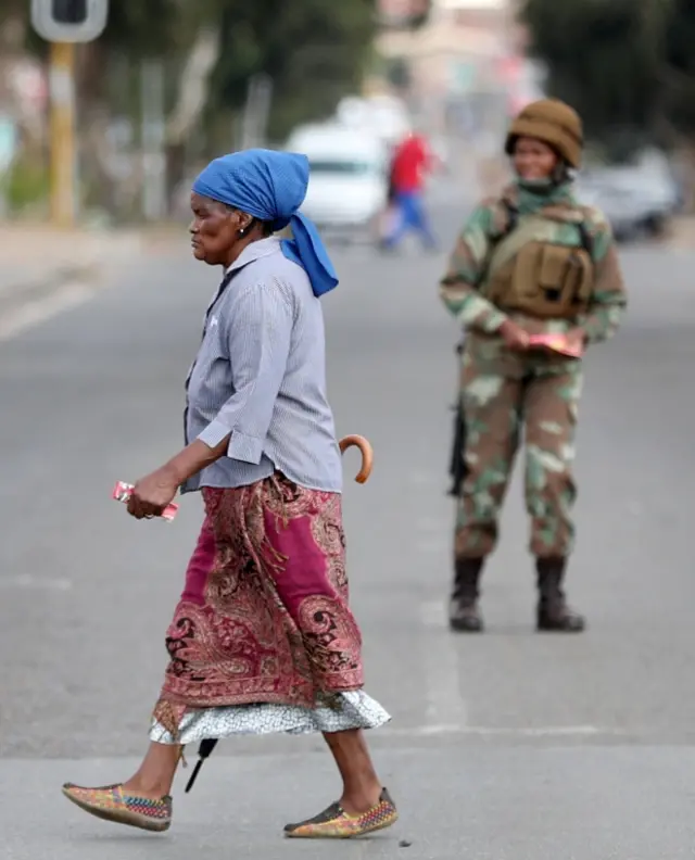 A woman walks past a member of the military in Soweto during national lockdown in South Africa. Photo: 23 April 2020