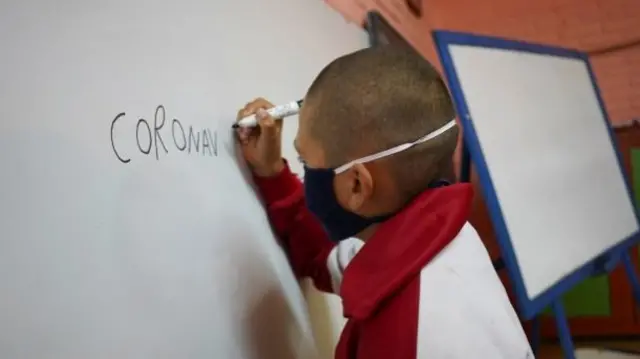 Student Juan Camacho writes the word "coronavirus" on a whiteboard during a lesson at Escuela 30, a rural school that has resumed classes after a month off due to the coronavirus disease (COVID-19), in San Jose, Uruguay April 22, 2020