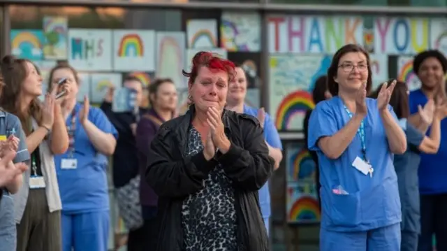 A woman looks emotional as she claps outside the Royal Derby Hospital