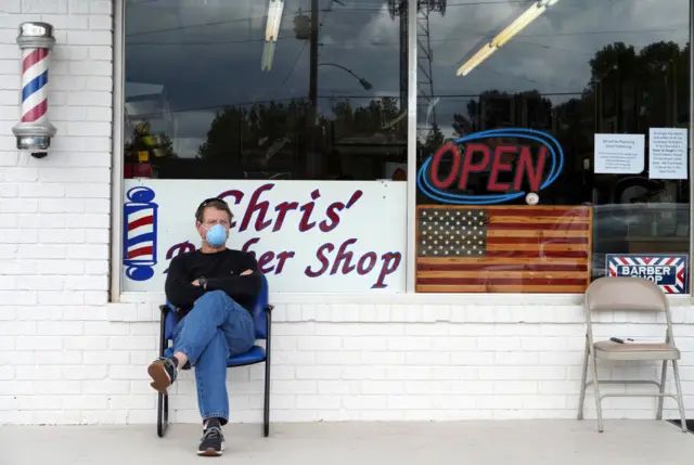 Dan Settle sits outside Chris' Barber Shop as he waits his turn for a haircut in Lilburn, Georgia on 24, April 2020