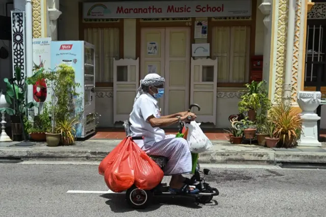 A man rides a mobility scooter while wearing a mask