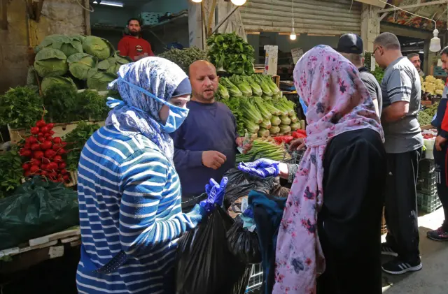 Women buy fresh vegetables at a market ahead of the Muslim holy month of Ramadan, during the novel coronavirus pandemic crisis in the Jordanian capital Amman, on April 23, 2020.