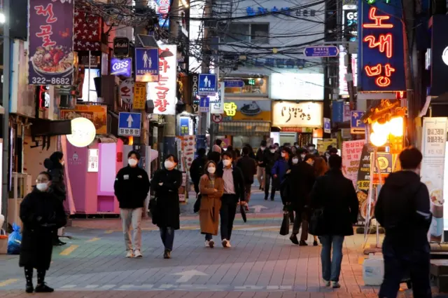 People wearing face masks walk on a street in Seoul