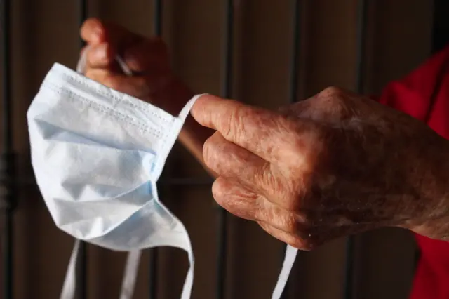 Elderly person holds a mask