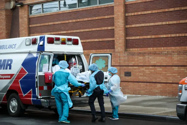 Healthcare workers are carrying a coronavirus patient to an ambulance by the Wyckoff Heights Medical Center in Brooklyn, New York City on 21 April