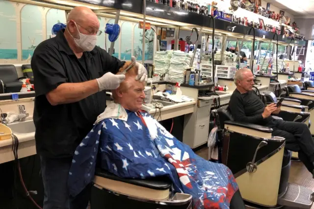 Barber Tommy Thomas, 69, who has been cutting hair for 50 years, gives his long-time customer Fred Bentley a haircut in Georgia after virus lockdown