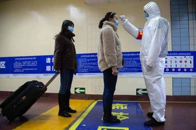 A health worker checks the temperature of a women in Beijing, China.