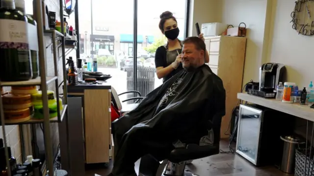 An Atlanta barber wears a face mask while cutting a customer's hair