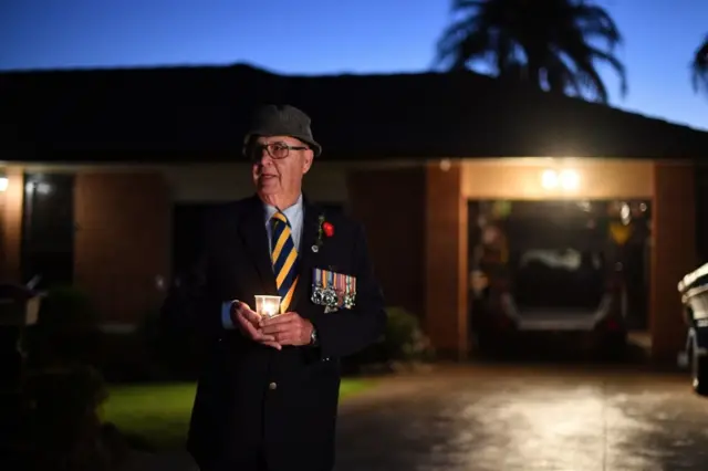 Veteran Peter McFarlinen holds a candle outside his home in Sydney