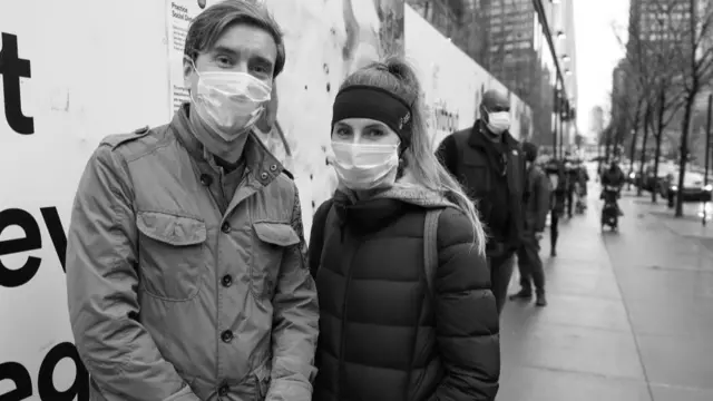 People wait in line for a shop wearing face masks