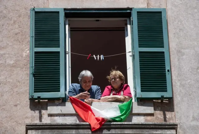 A couple in the San Lorenzo district of Rome hold a flag out of their window