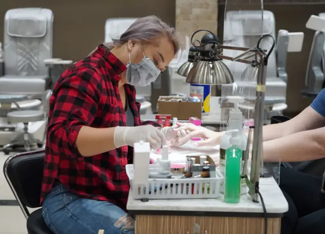 A customer having their nails done behind PPE in Atlanta, Georgia