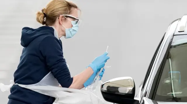 A nurse takes a swab at a Covid-19 drive-through testing station