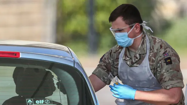 A member of the military takes a swab at a drive-through testing centre