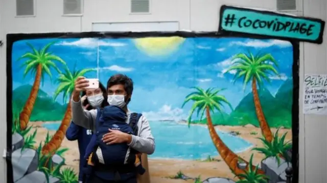 Two people take a picture while wearing a mask