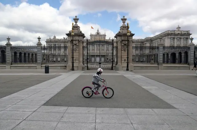 A girl rides her bike past the Royal Palace in Madrid