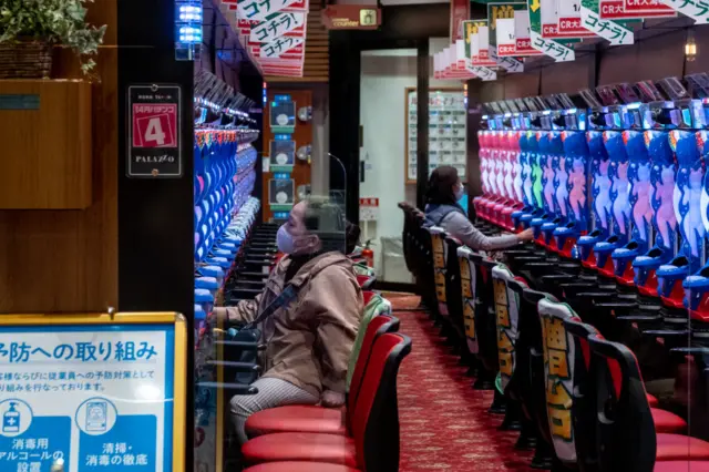 Women wearing preventive masks as a precaution against the spread of Coronavirus play pachinko