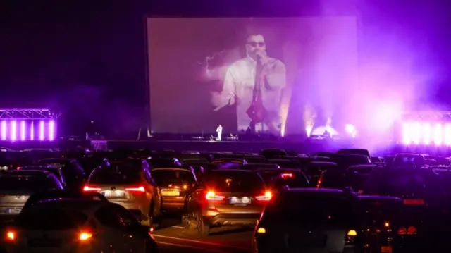 Cars in front of a stage with singer