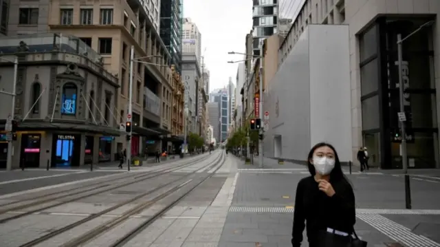 Woman wears a mask in the deserted city centre of Sydney