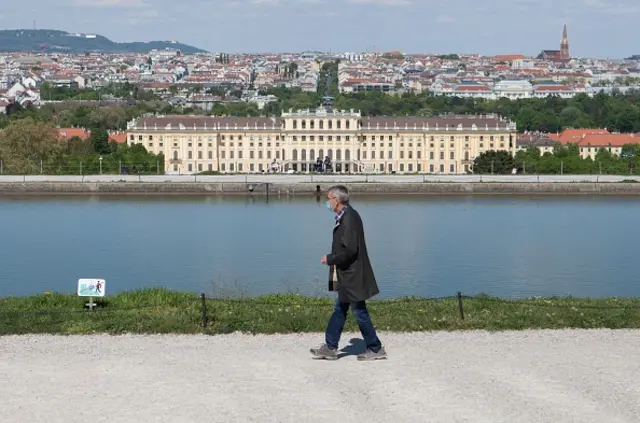 A man with a protective mask walks by the Gloriette in front of Schoenbrunn Palace in Vienna