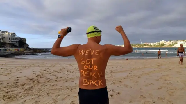 Swimmer at Bondi with the words 'We've got our beach back' written across his back