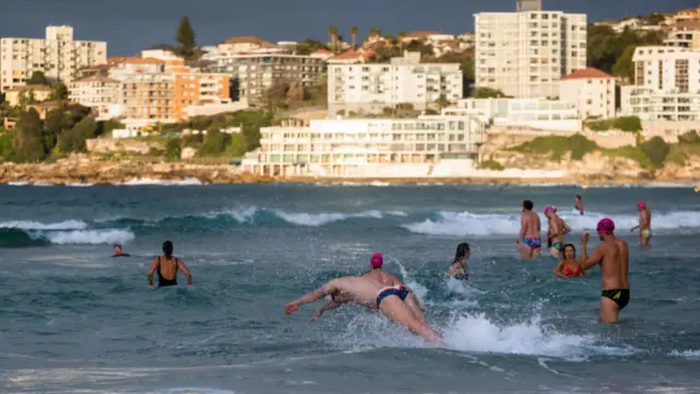 Swimmers dive into the water at Bondi Beach