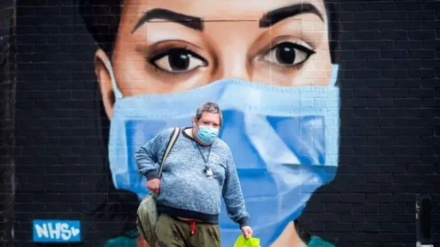 A woman in a mask in front of a mural