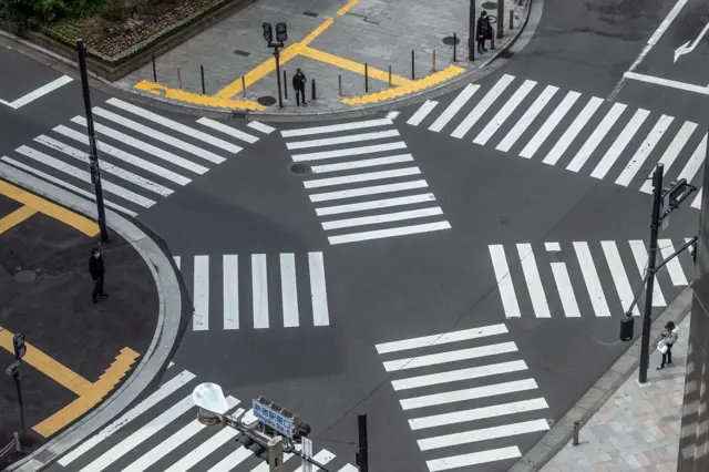 People wait to walk over a pedestrian crossing in Shinjuku