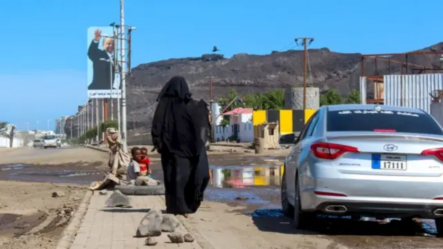 A woman begs for money with her children on a street in Aden, Yemen (27 April 2020)