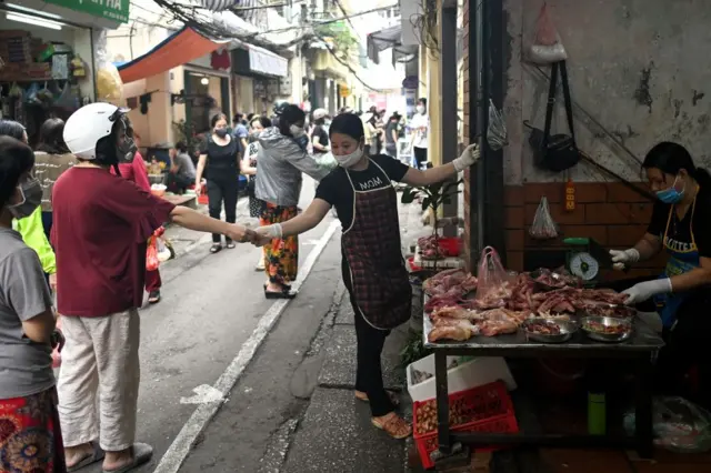 Residents wearing face masks practise social distancing, Hanoi