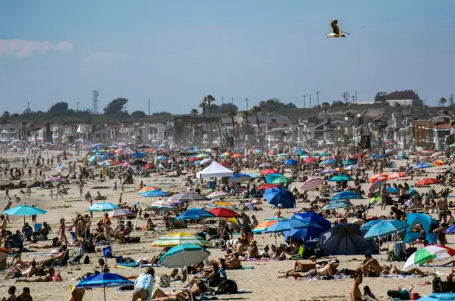 Large crowds gather near the Newport Beach Pier in Newport Beach on Saturday, 25 April, 2020 to cool off during the hot weather despite the coronavirus pandemic