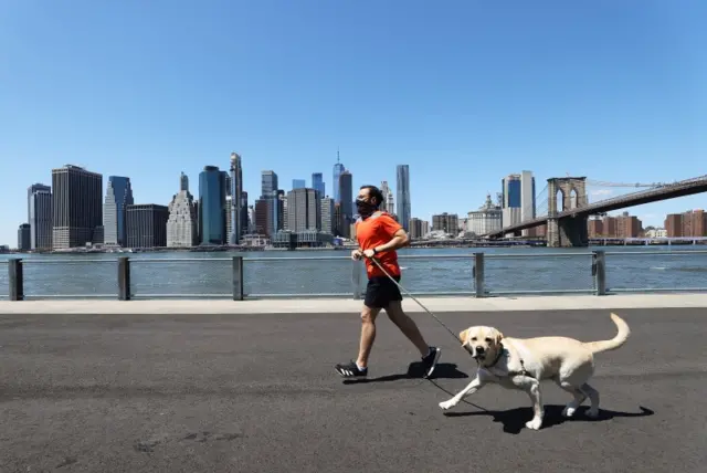 A man wearing a mask runs with his dog in New York