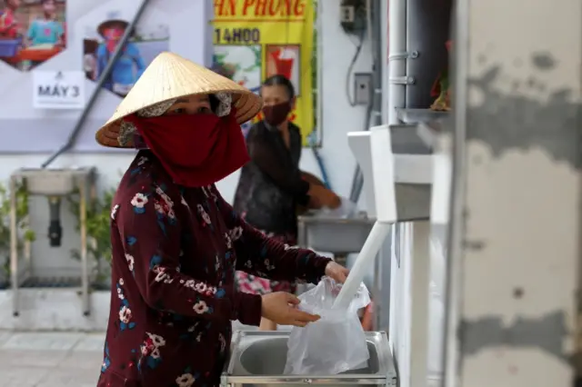 A woman fills a plastic bag with rice from a 24/7 automatic rice dispensing machine "Rice ATM" during the outbreak of the coronavirus disease (COVID-19), in Ho Chi Minh, Vietnam, April 11, 2020.