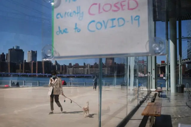 A woman walks her dog while wearing a mask