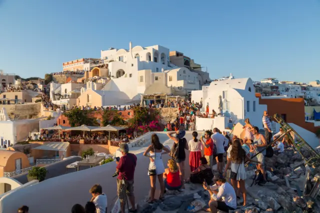 Tourists gather to watch the sun set in Santorini