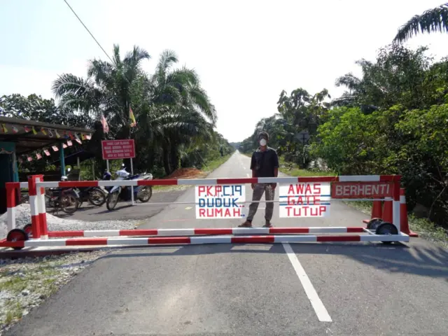 A villager stands behind a barricade in Malaysia