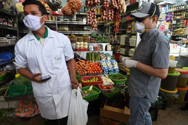 Shoppers wear face masks to prevent the spread of the new coronavirus at a neighborhood market in Lima