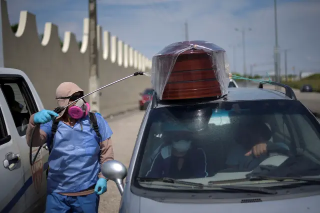 A worker sprays disinfectant on a vehicle carrying a coffin lined up to enter a cemetery as Ecuador"s government announced on Thursday it was building a "special camp" in Guayaquil for coronavirus disease (COVID-19) victims, in Guayaquil, Ecuador April 2