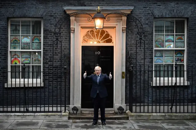 Britain's Prime Minister Boris Johnson gives a thumbs up gesture after participating in a national "clap for carers" to show thanks for the work of Britain"s NHS (National Health Service) workers and other frontline medical staff around the country as they battle with the novel coronavirus pandemic, in the doorway of 10 Downing Street in central London